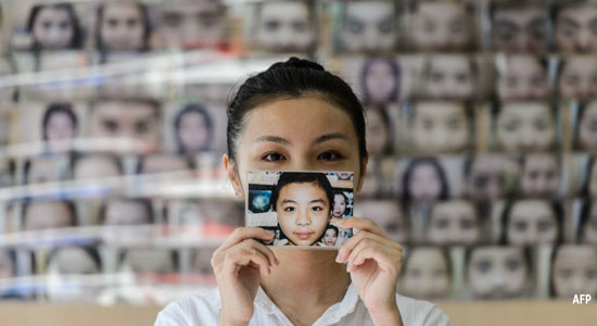 Daisy Tse, a customer of face reader Li Chau-jin, holds up a photograph of herself showing her eyebrow shape before and after having them plucked.